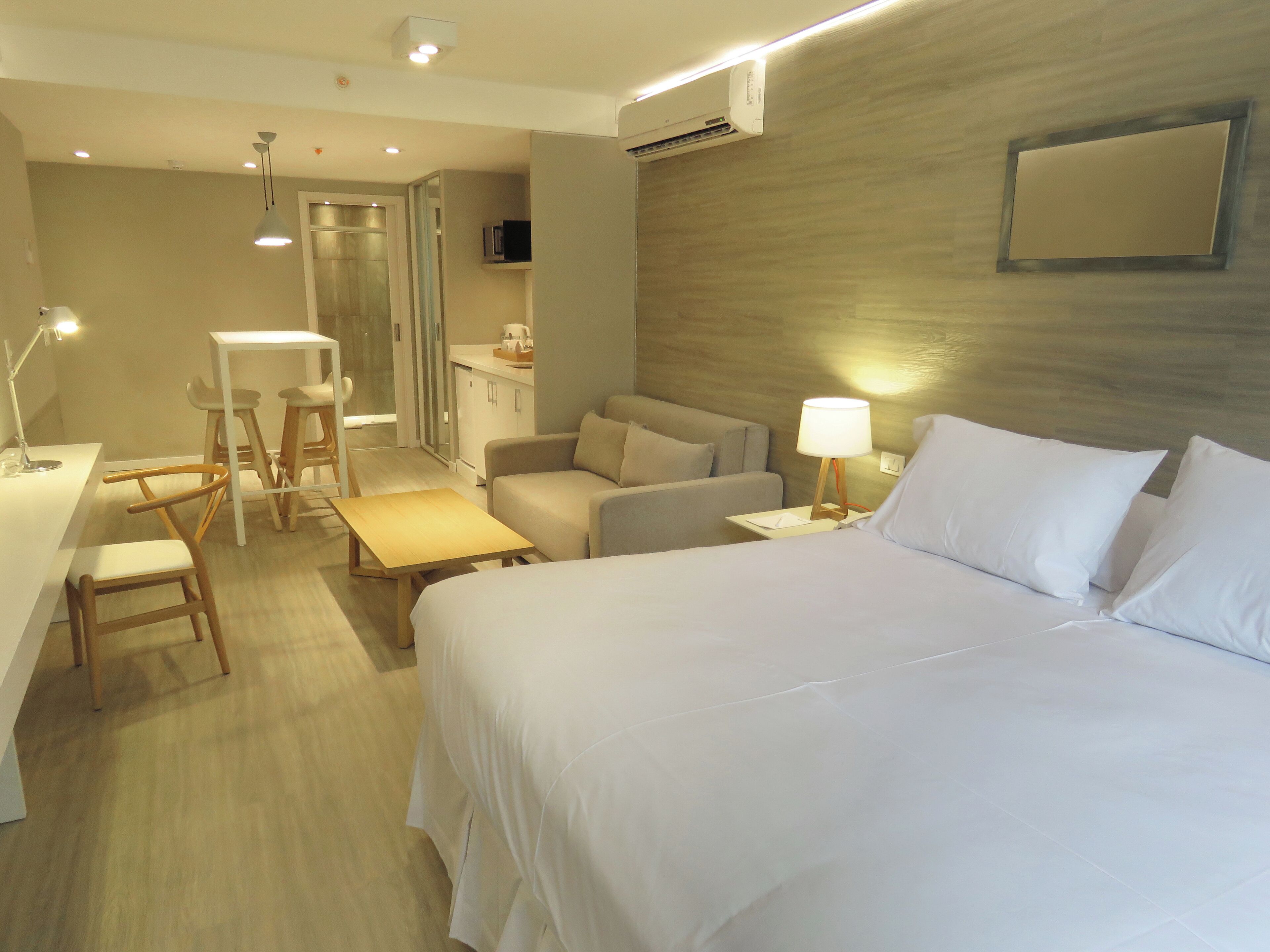 Una habitación de hotel con una cama, un escritorio, una silla, un sofá y una mesita.