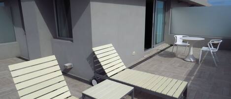 A modern outdoor seating area with white lounge chairs and a small round table.