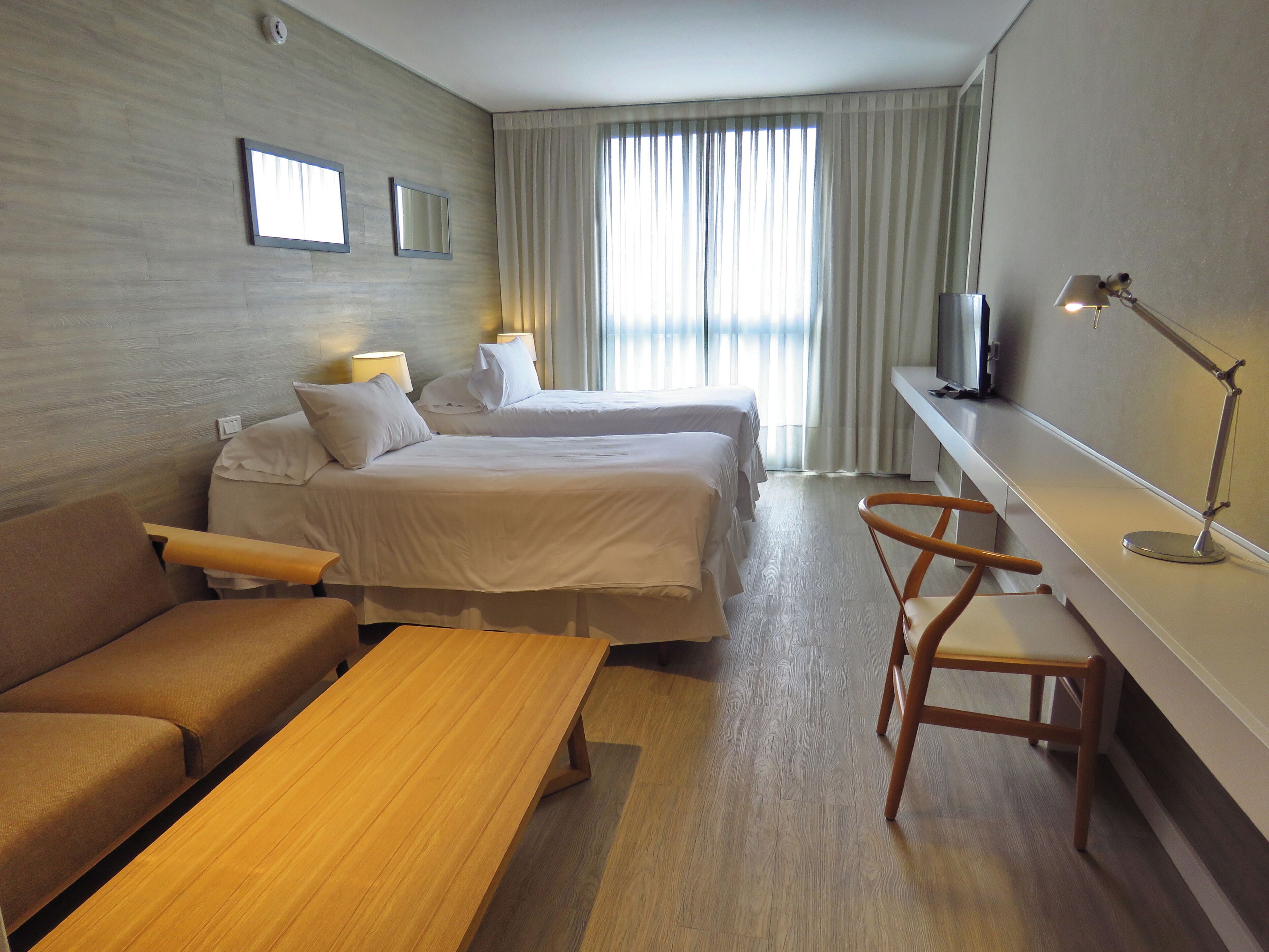 Habitación de hotel con dos camas, un sofá, un escritorio y una silla.
