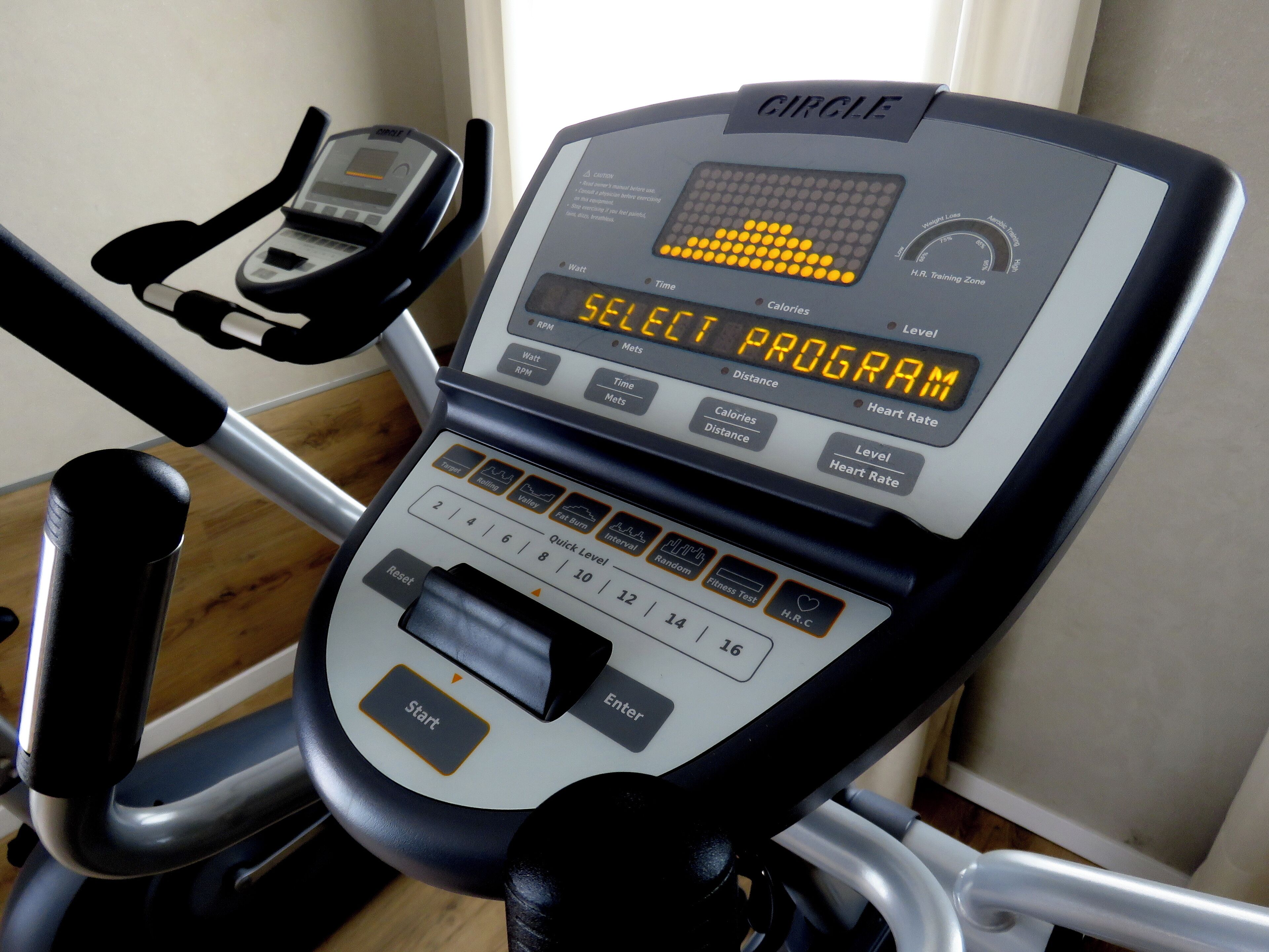 A treadmill with a digital display, control panel, and foot pedals.