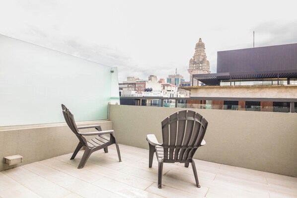 A balcony with two chairs and a view of a historic building in the background.