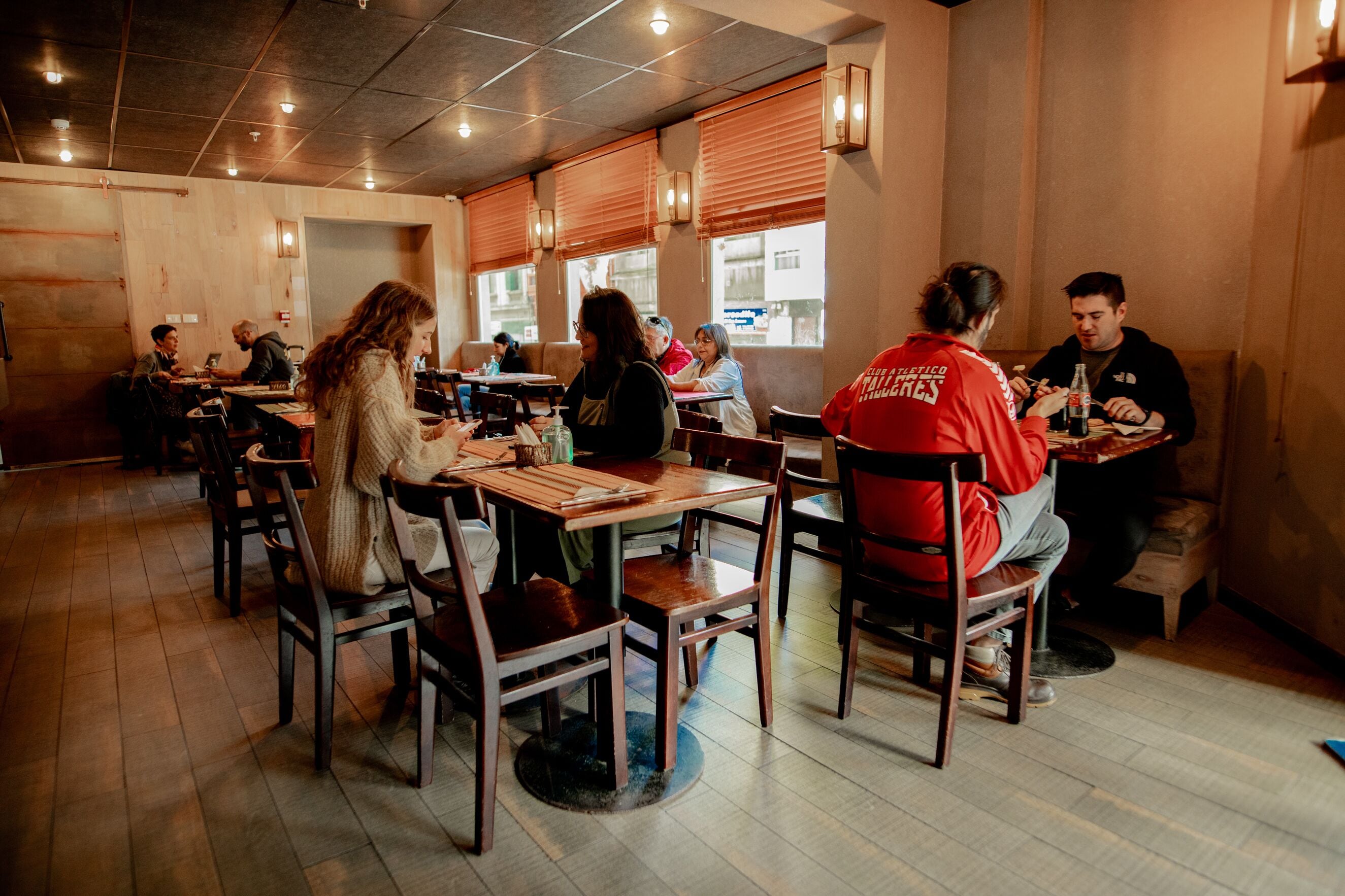 A restaurant with wooden tables and chairs, a tiled floor, and a warm interior.
