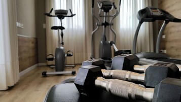 Un gimnasio en casa con equipo de ejercicio, incluyendo mancuernas, una bicicleta estática y una cinta de correr.