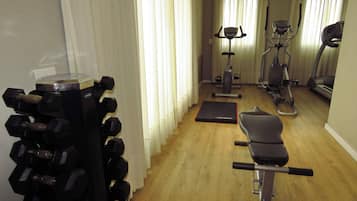 A home gym with exercise equipment including dumbbells, a bench, a stationary bike, and an elliptical trainer.