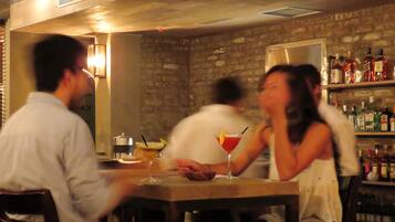 A bar area with a brick wall, wooden ceiling, and shelves with bottles.