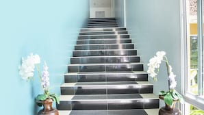 Una escalera con peldaños de colores blanco y negro, flanqueada por dos jarrones marrones con flores blancas.