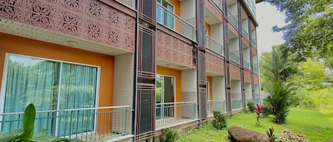 Un hotel de varios pisos con balcones, un jardín y una variedad de plantas.