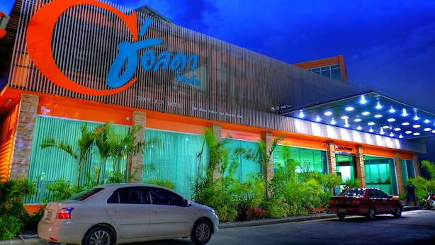 Un hotel con un llamativo letrero naranja y azul, fachada moderna y exterior bien cuidado.