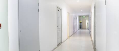 A long, narrow hallway with white walls and doors on both sides.