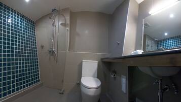Une salle de bain avec douche, toilettes et lavabo.