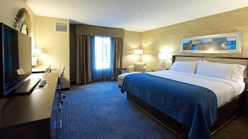 A hotel room with a bed, desk, chair, and a television.