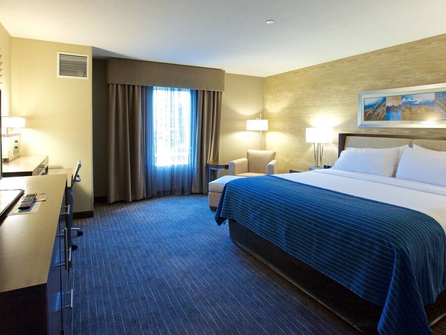 A hotel room with a bed, desk, chair, and a television.