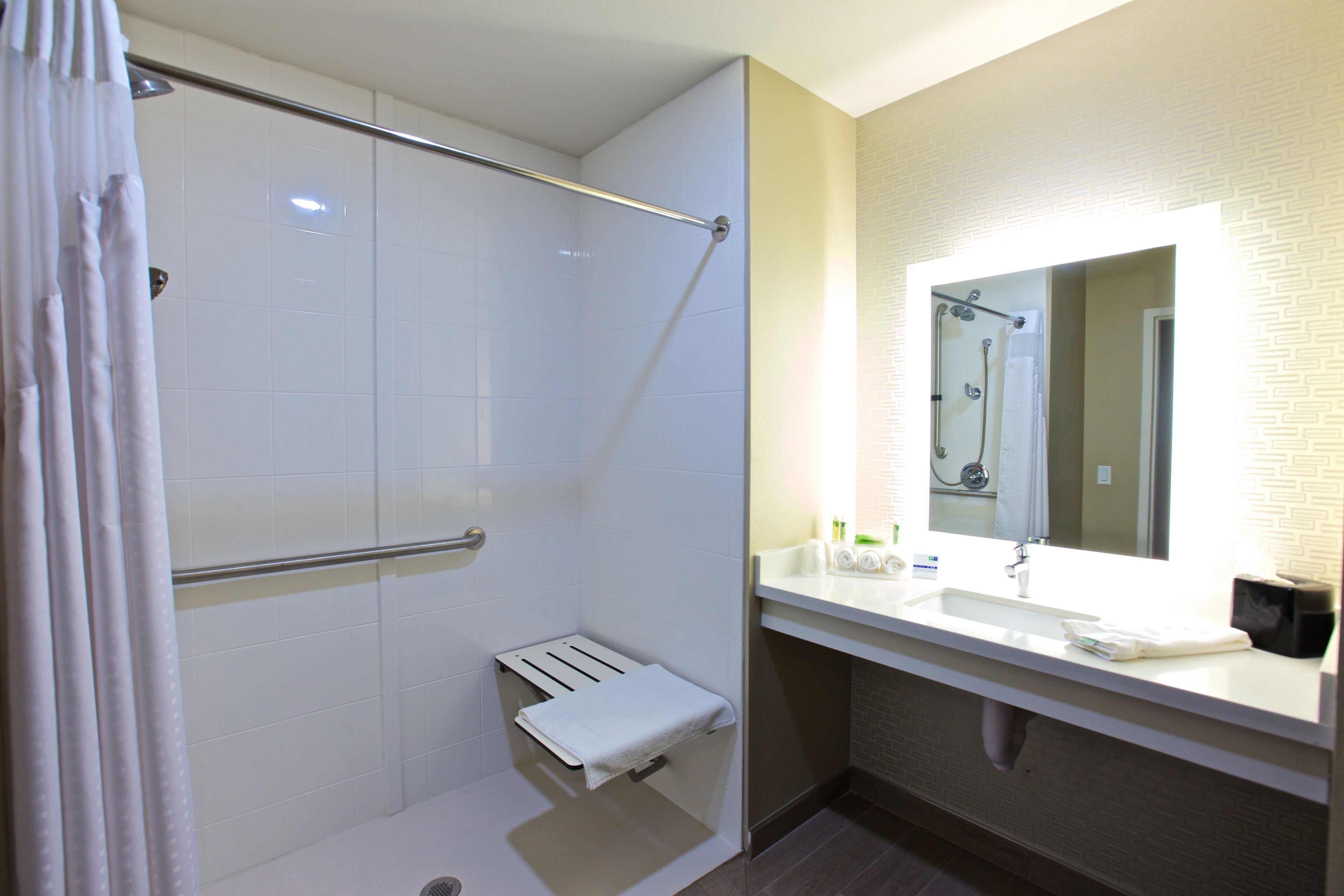 A modern bathroom with a shower, a towel rack, a sink, and a mirror.