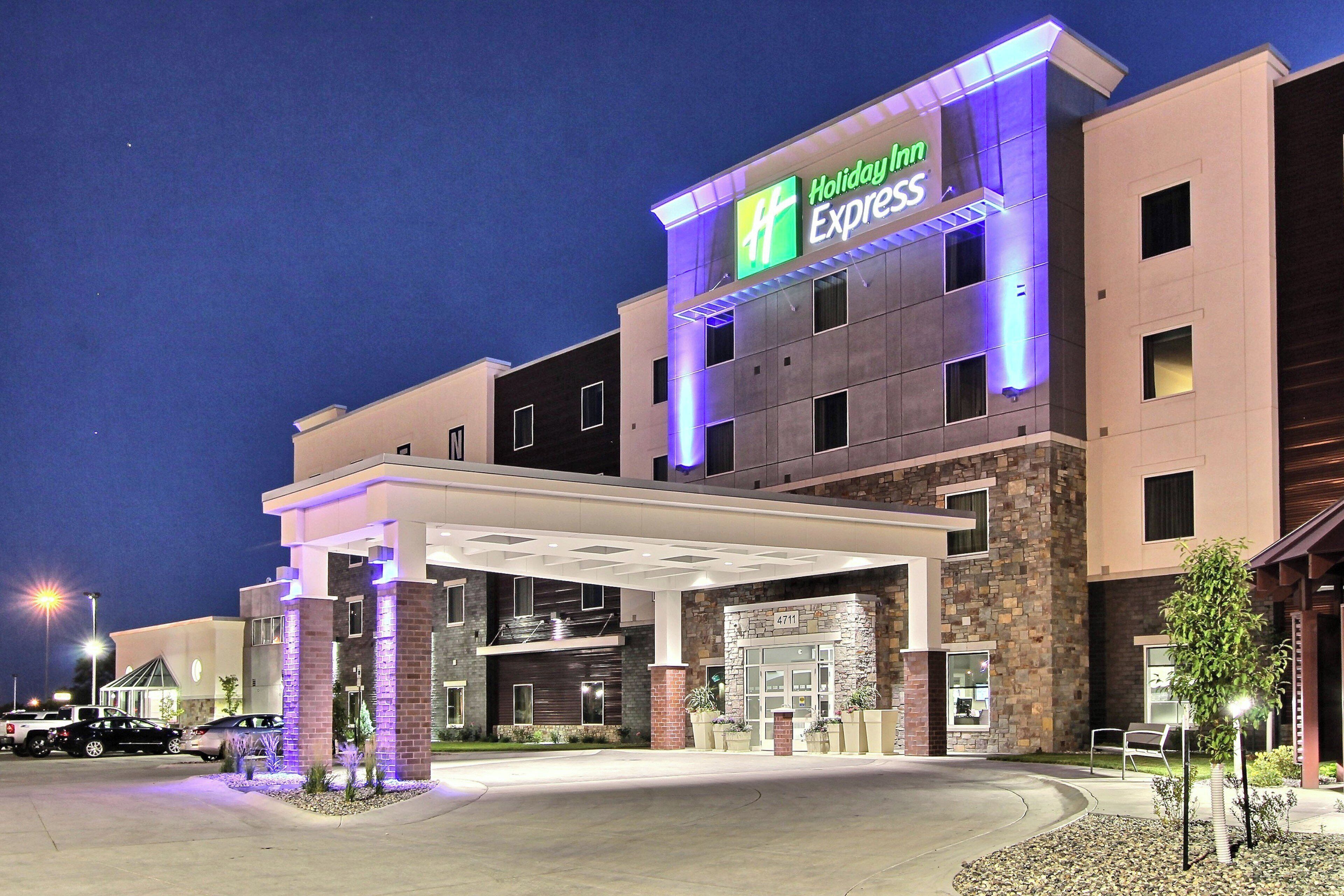Un hotel Holiday Inn Express con vestíbulo techado y fachada de piedra.
