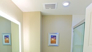 Ein Badezimmer mit einem weißen Waschbecken, Spiegel und Toilette. An der Wand hängt ein gerahmtes Bild und es gibt einen Handtuchhalter.