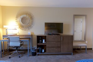 A hotel room with a desk, chair, TV, cabinet, and a sunburst wall decoration. - Holiday Inn Express Fargo SW - I-94 Medical Center by IHG (Fargo)