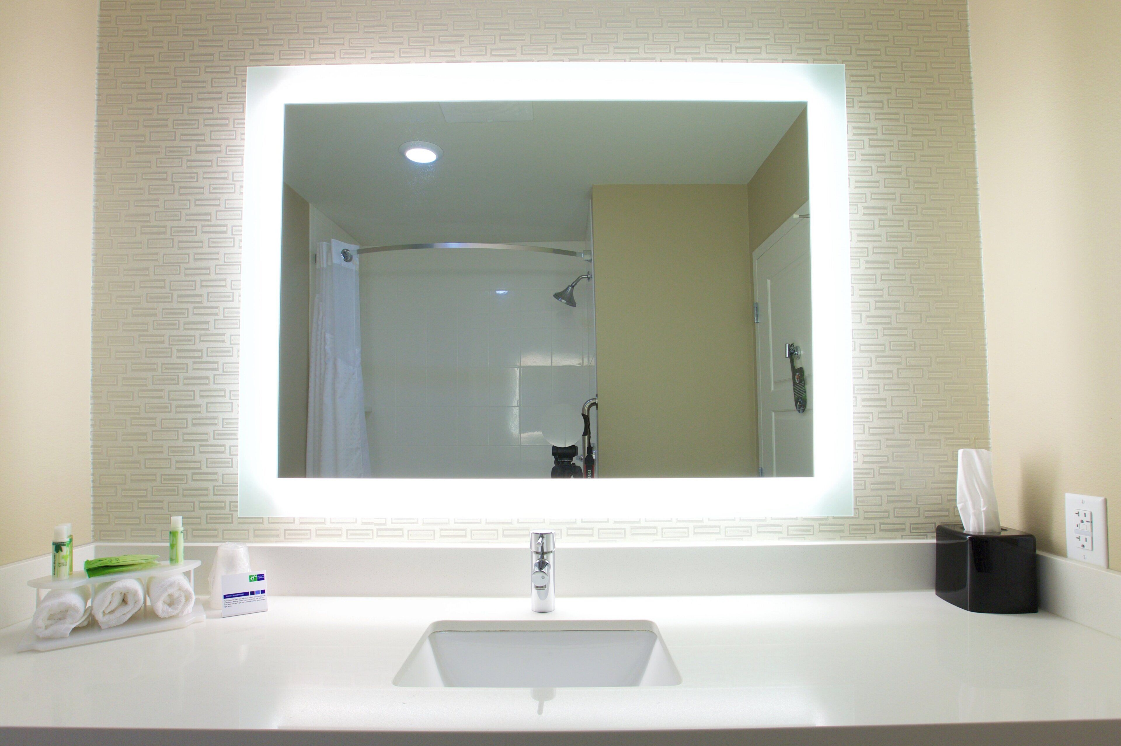Une salle de bain avec un grand miroir, un lavabo et une douche.