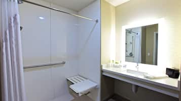 A bathroom with a shower, a toilet, a sink, and a mirror.
