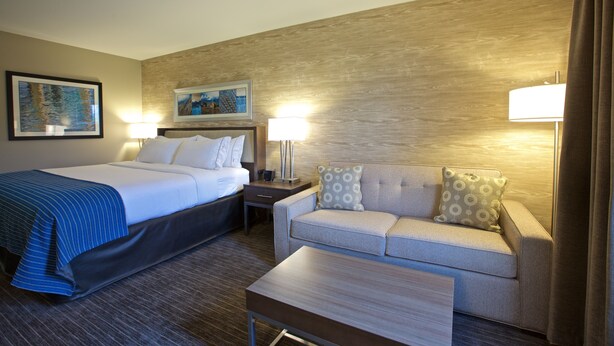 Ein Hotelzimmer mit einem Bett, einem Sofa, einem Tisch und zwei Lampen.