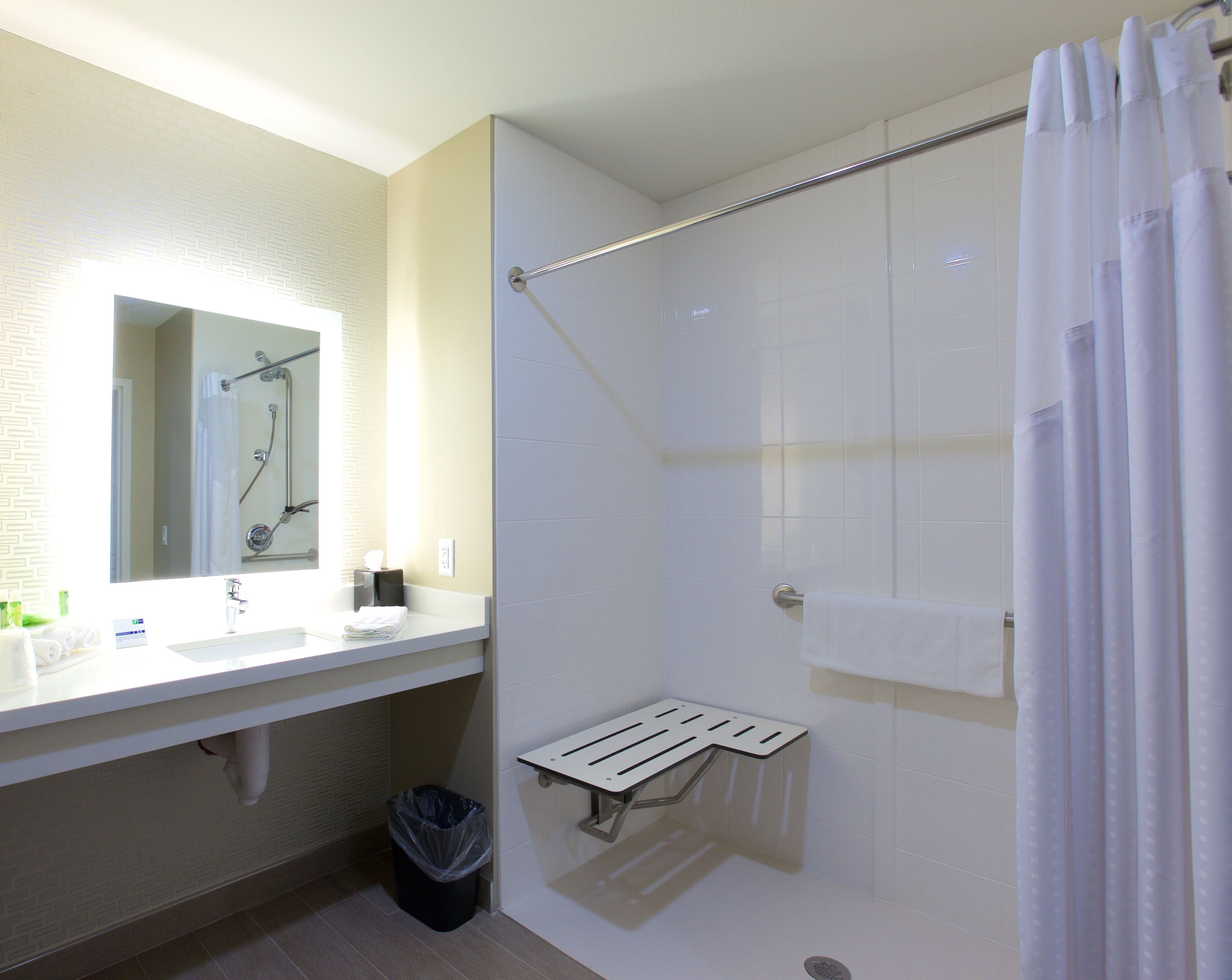 A modern bathroom with a white sink, mirror, and shower.