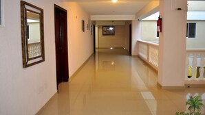 A hotel corridor with a wooden door, framed mirror, and a fire extinguisher. - Le Paradis S. Hotel (Cap-Haitien)