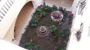 A courtyard with a fountain, potted plants, and a decorative structure. - Le Paradis S. Hotel (Cap-Haitien)
