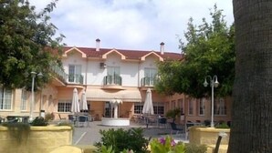 A hotel with a central courtyard, outdoor seating, and a fountain. - Hotel Mitra (Cabra)