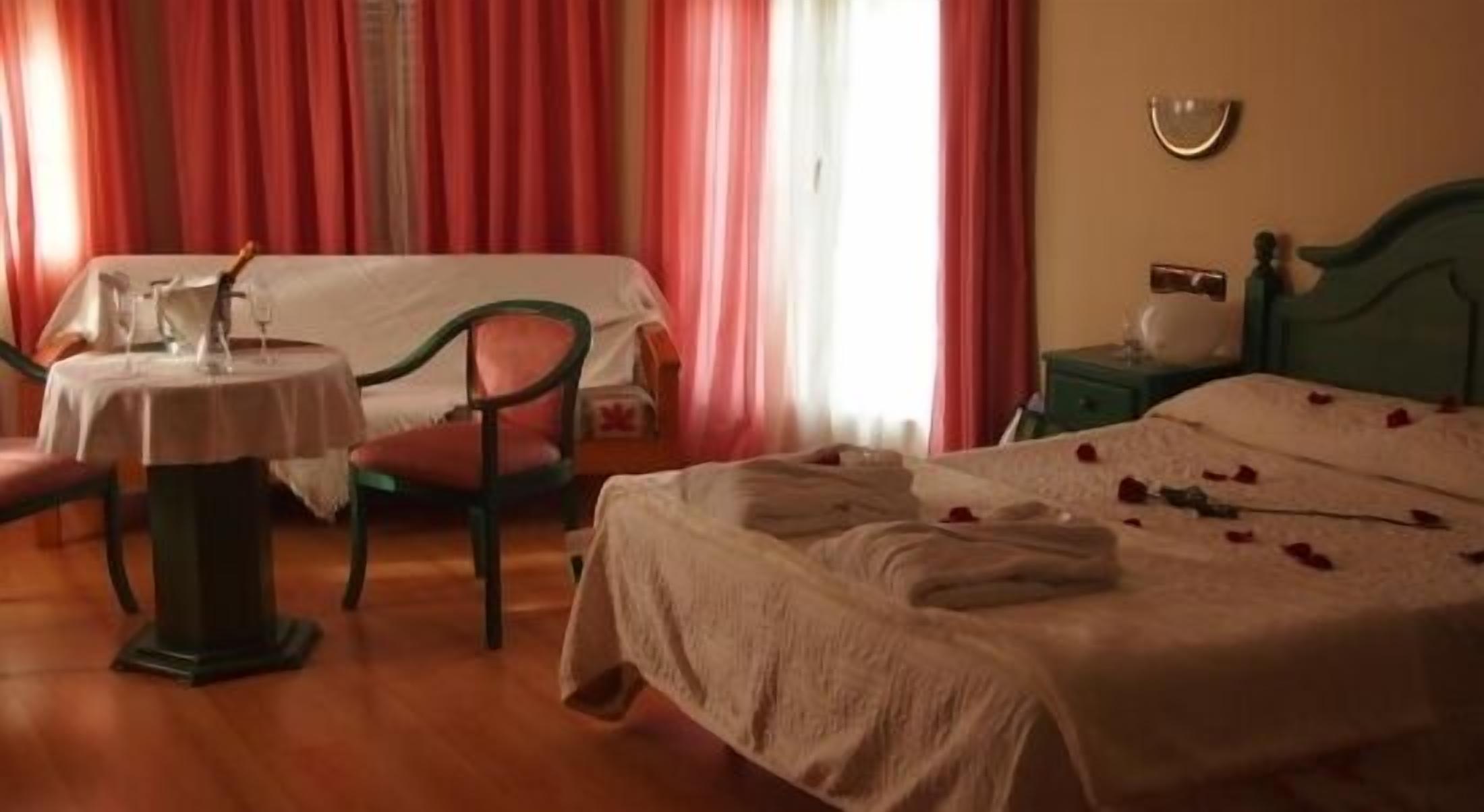 Een hotelkamer met een bed, een stoel, een klein tafeltje en een nachtkastje.