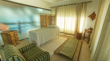Relax in a cozy space with a neatly made bed, sofa, and wooden nightstand.