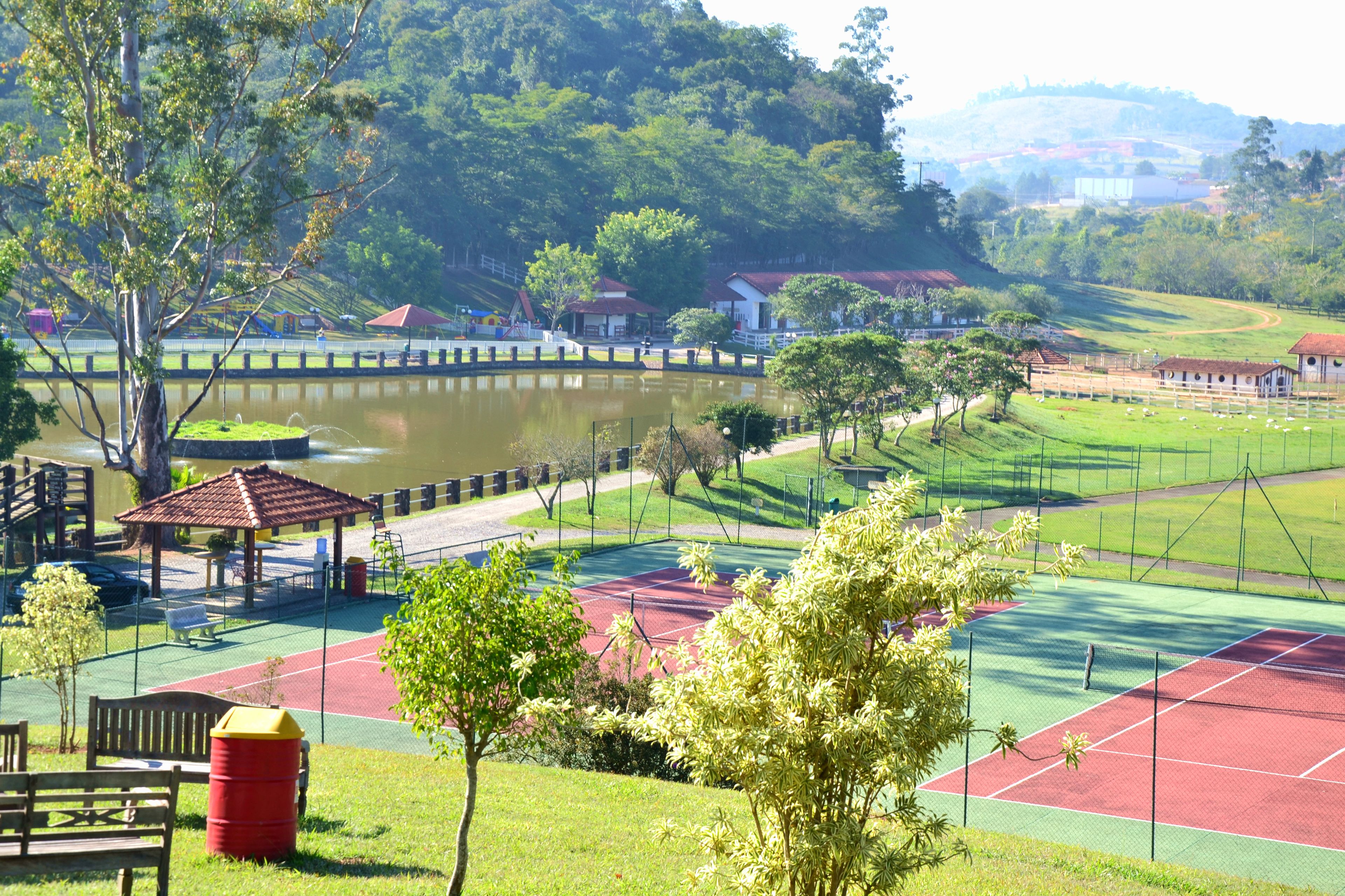 A park with a tennis court, a pond, and a gazebo.