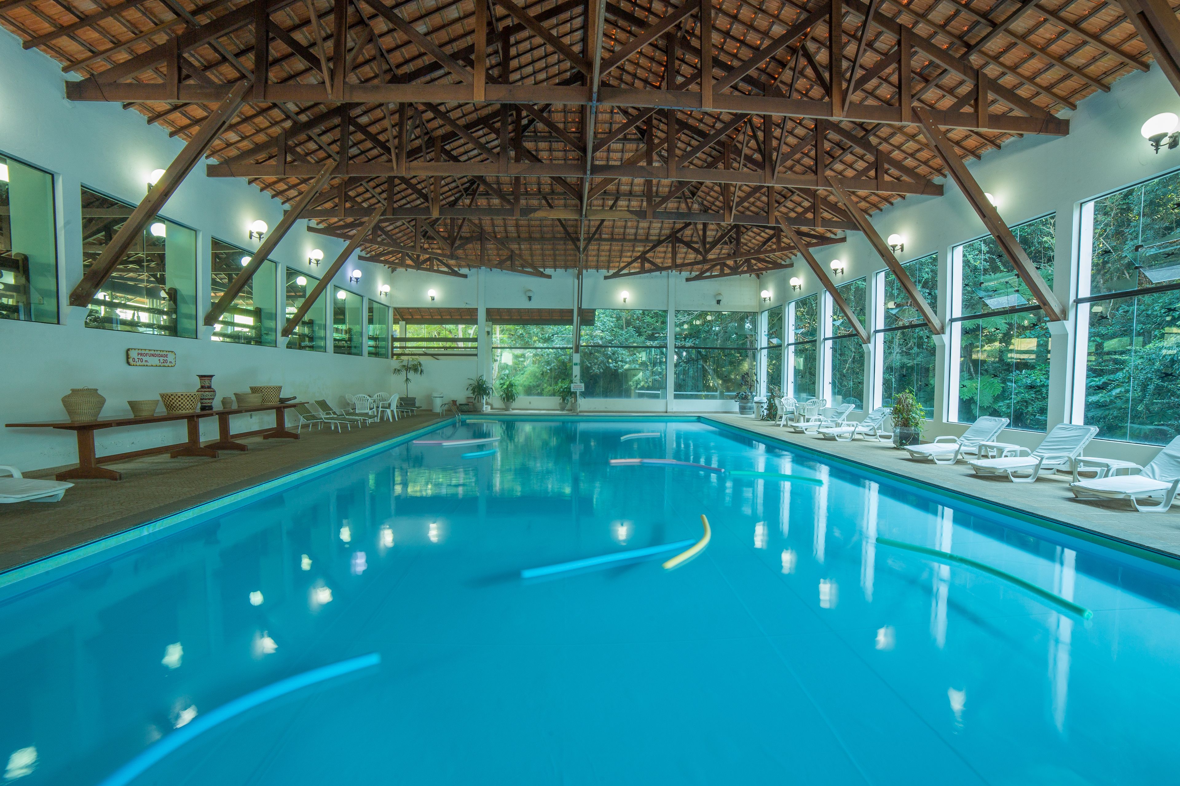 A swimming pool with a wooden ceiling and large windows.