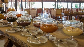 A buffet with various food items in glass containers, each labeled with the dish name.