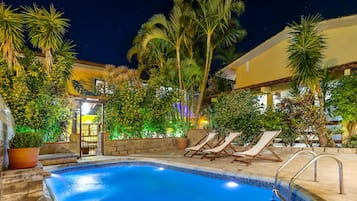 Una piscina al aire libre, sombrillas, sillones reclinables de piscina