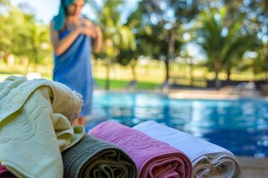 A poolside area with towels and a person in the background.