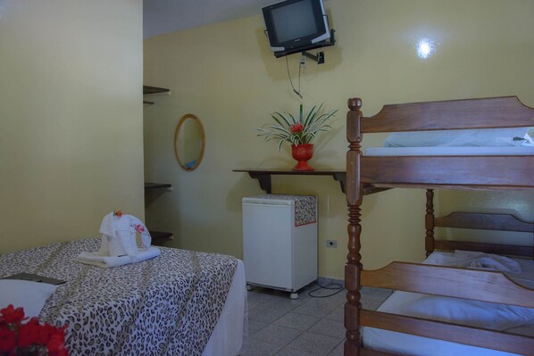 Una habitación con literas, un refrigerador pequeño, un televisor montado en la pared y una planta en maceta sobre una estantería.