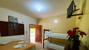 Une chambre avec deux lits, une télévision, une plante et une porte donnant sur l’extérieur.
