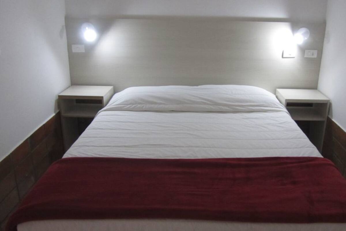Ein Hotelzimmer mit einem Bett, zwei Nachttischen und einer roten Tagesdecke.