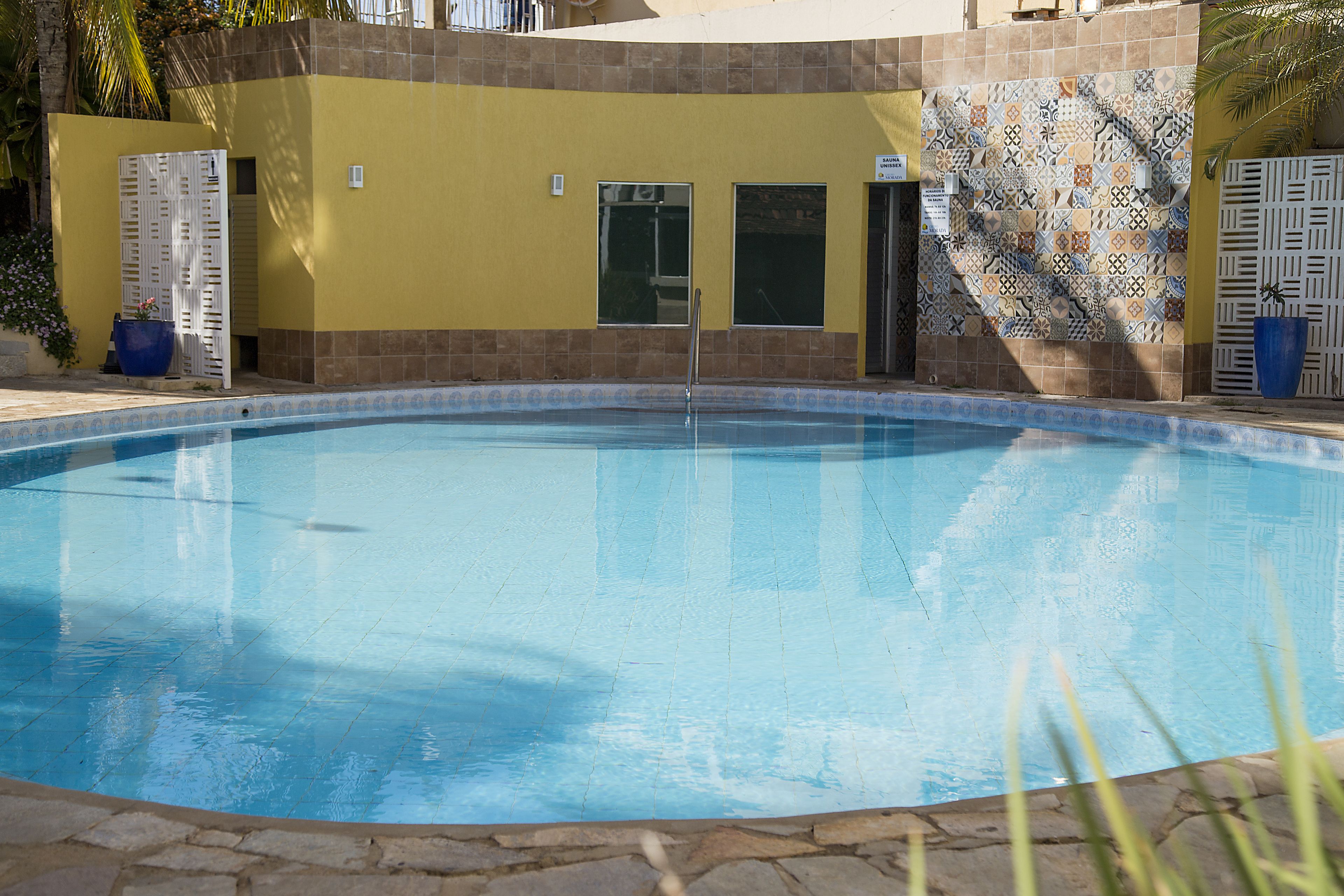 A swimming pool with a tiled wall and a stone border.