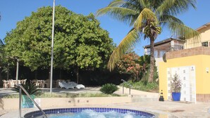 Una piscina con borde de azulejos azules, rodeada por un suelo de piedra.