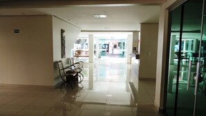 Un pasillo amplio con un banco, una puerta de cristal y un letrero que indica una ubicación.