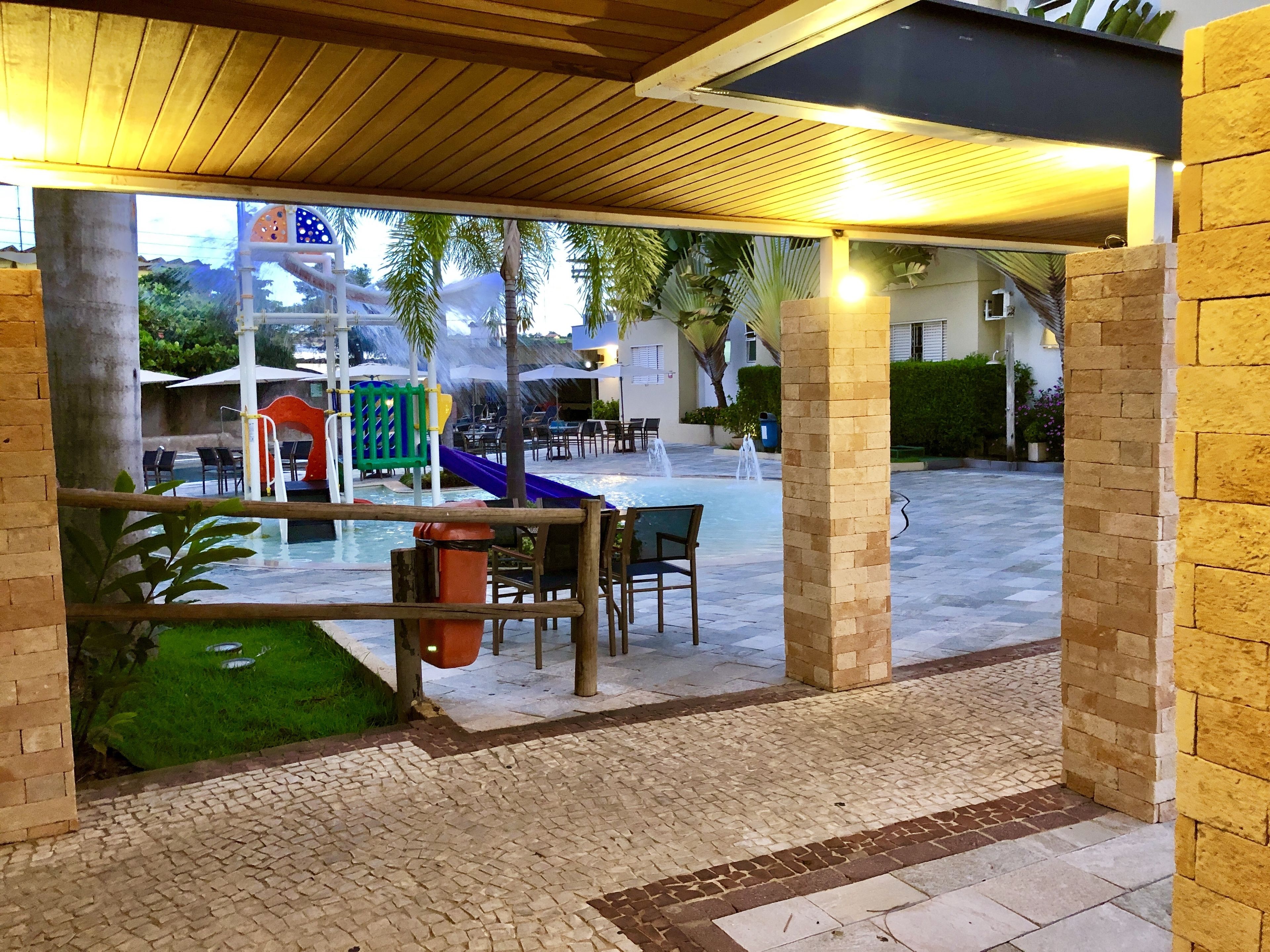 An outdoor patio area with a pool, seating, and a children's play structure.