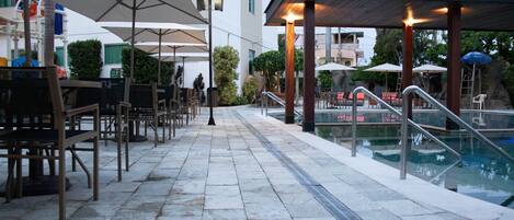 A poolside area with outdoor seating and umbrellas.