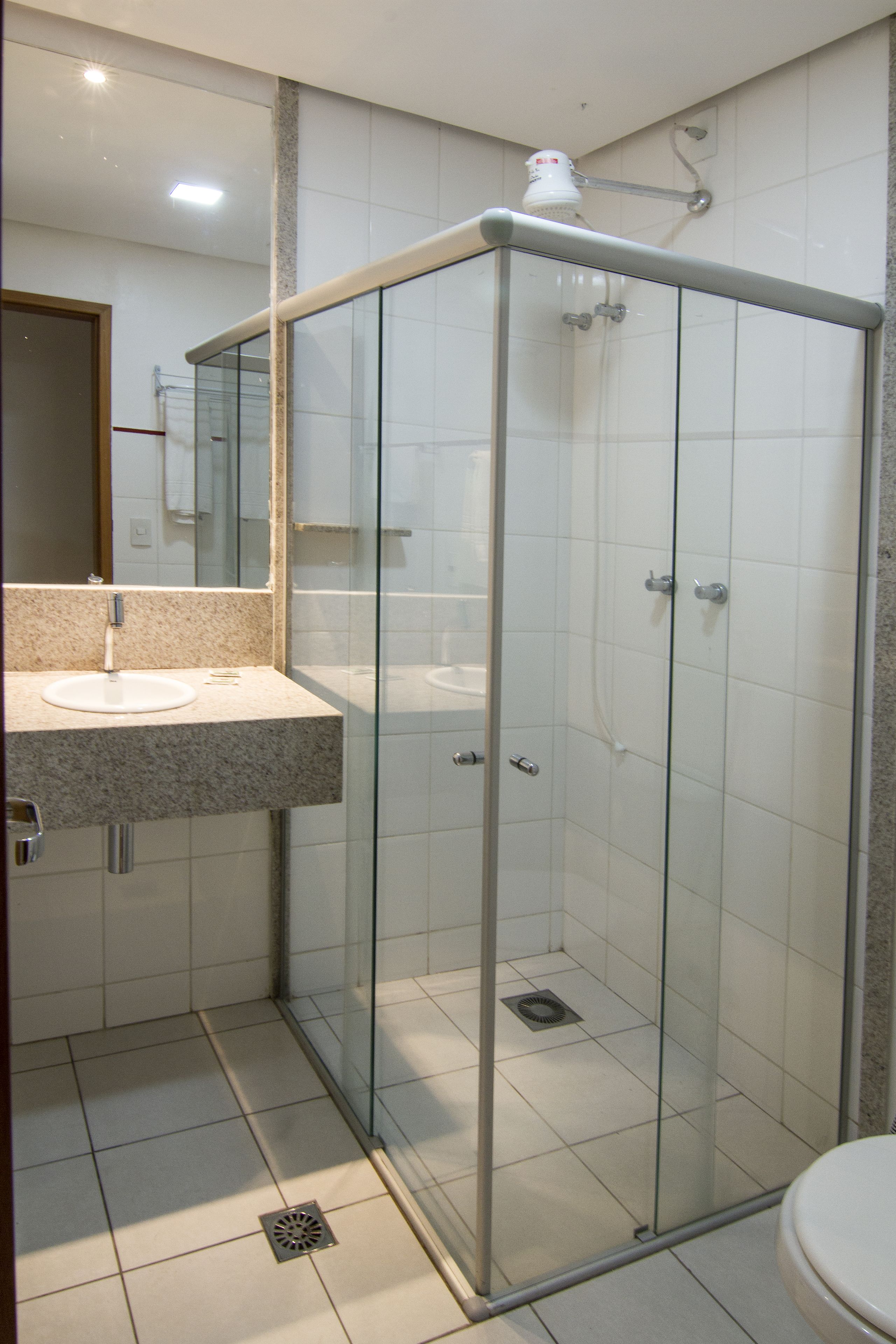 A modern bathroom with a glass-enclosed shower, a sink with a granite countertop, and a toilet.