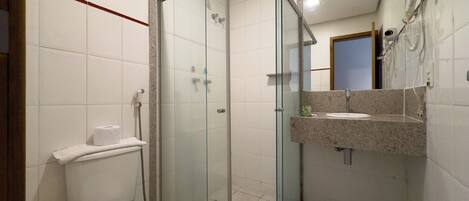 A bathroom with a glass-enclosed shower, a toilet, and a sink with a mirror above it.