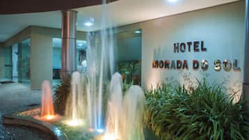 Entrada de um hotel com um recurso de água e uma placa indicando "HOTEL MORADA DO SOL".