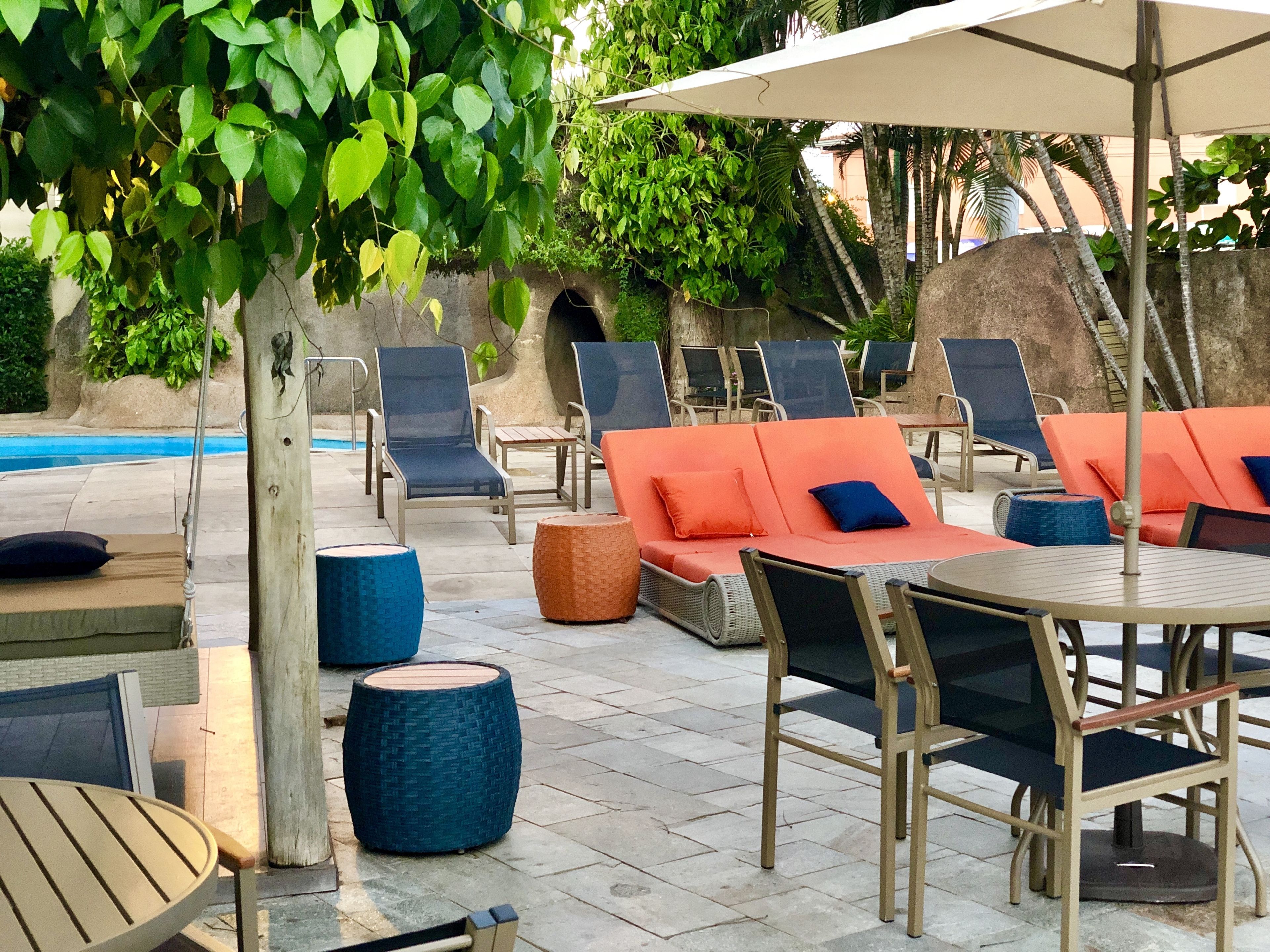 Ein Poolbereich mit Liegestühlen, einem Tisch und einem Sonnenschirm.