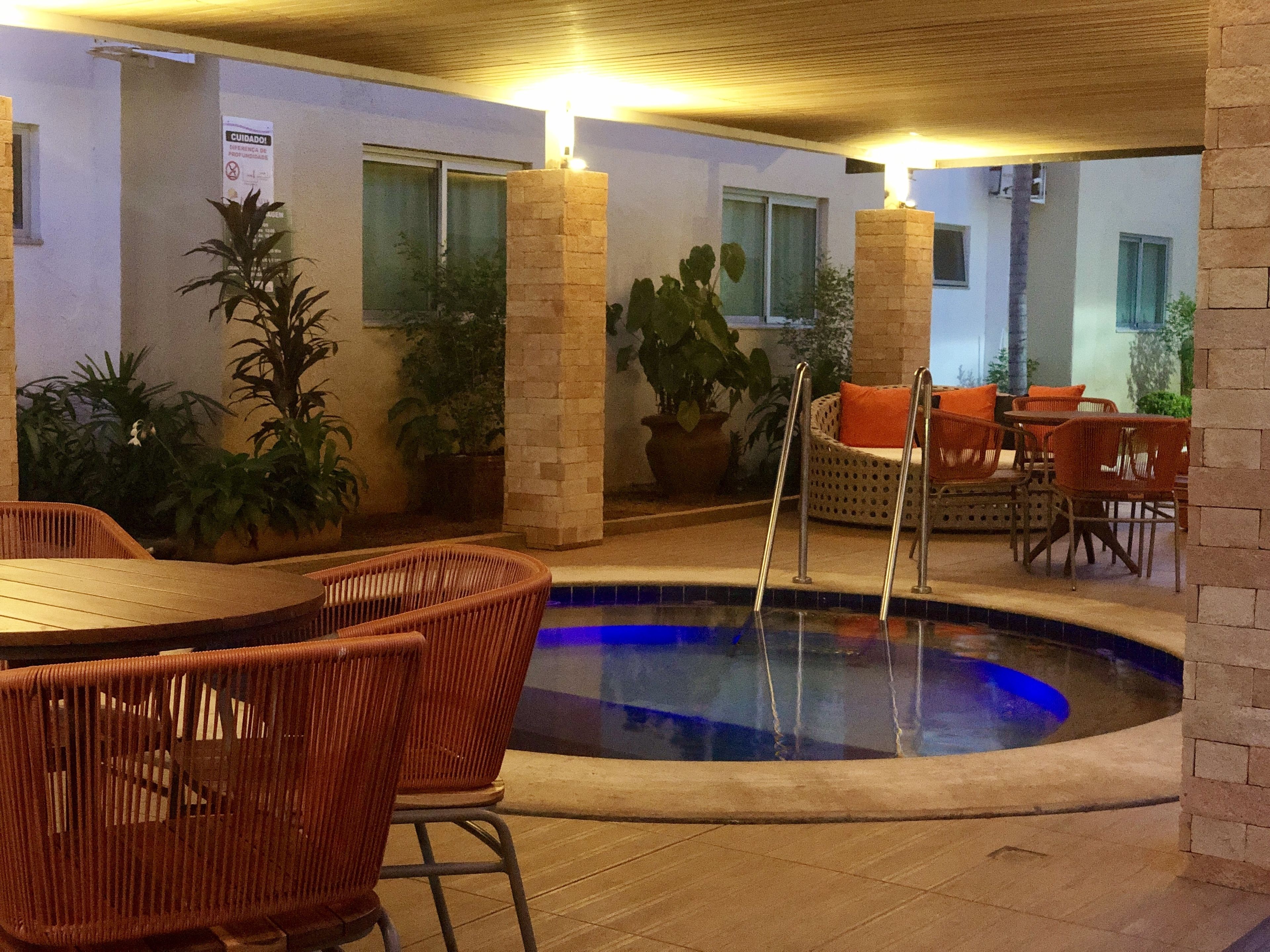 An indoor pool area with wicker furniture and potted plants.