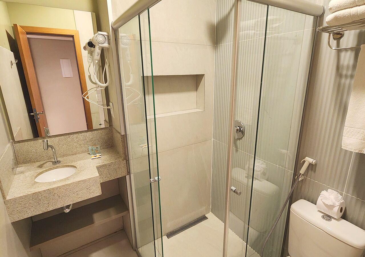 Une salle de bain moderne avec une douche à parois de verre, un lavabo avec un miroir et des toilettes.