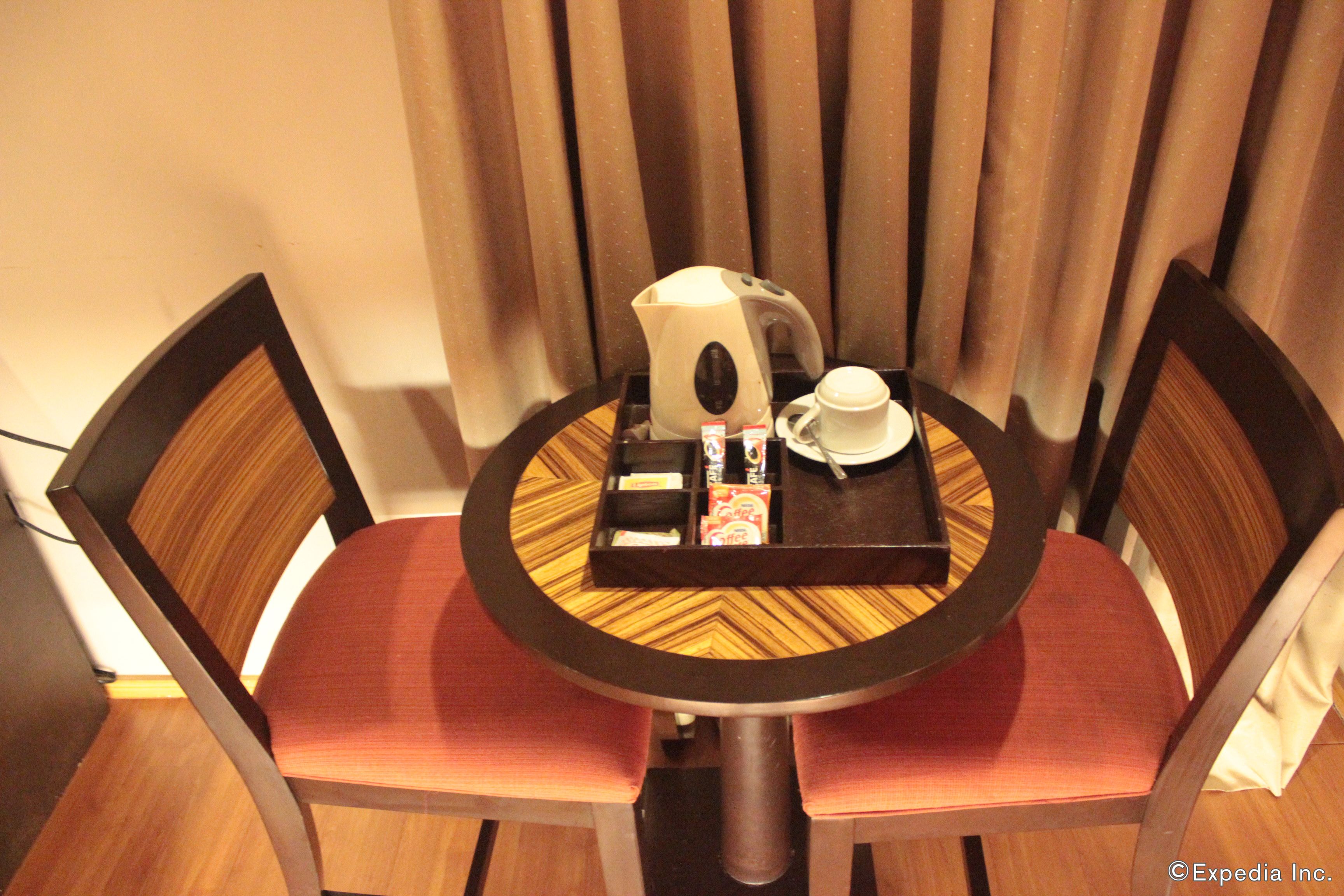 A small round table with a tray containing a teapot, cups, and a box of tissues.