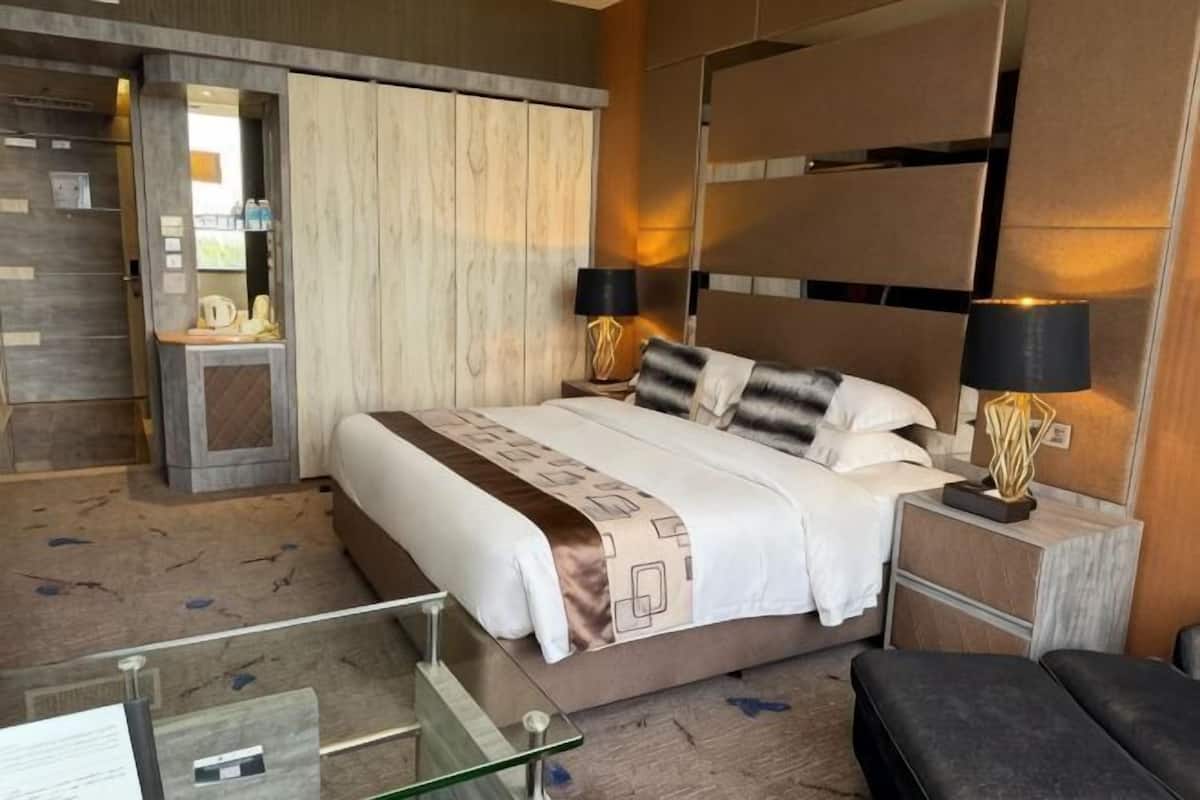 A hotel room with a large bed, bedside lamps, a glass coffee table, and a seating area.